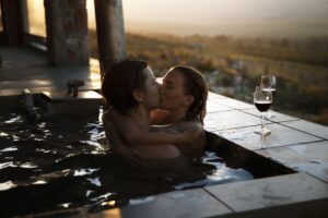 In love couple kisses each other in a bathtub with a fantastic view and a good glass of wine