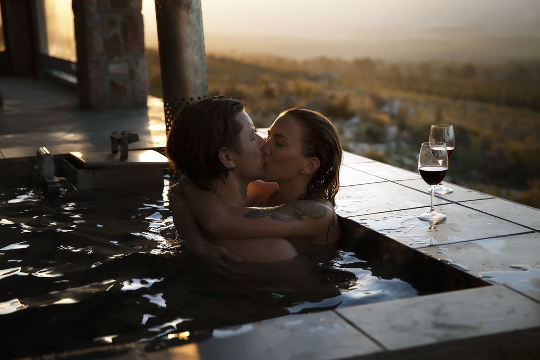 Verliefd stelletje zoent elkaar in een bad met een fantastisch uitzicht en een goed glas wijn