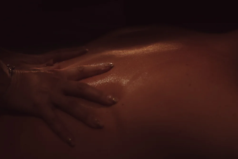 Erotische massage van een sensuele escort die haar handen over de rug van haar man laat glijden