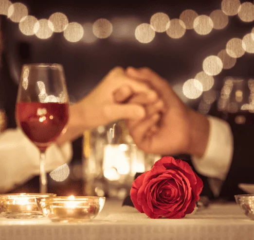 Romantic dinner of two people holding hands drinking champagne and having a good time